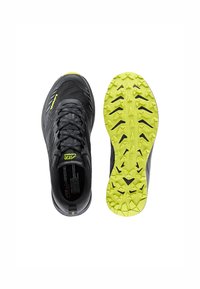 Black athletic shoes featuring a textured upper with reflective accents, a cushioned sole, and a bright yellow outsole with aggressive tread patterns.