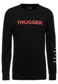 Sudadera negra de mangas largas con el texto en rojo "THUGGER" en la parte frontal y nombres de ciudades impresos verticalmente en la manga izquierda en blanco.