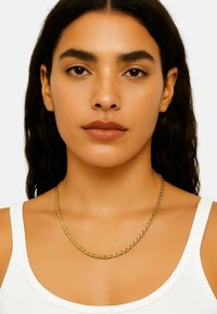 Gouden gedraaide kettinghalsband op een persoon die een witte tanktop draagt. Gladde oppervlakte met een metallic glans, rustend op het sleutelbeen.