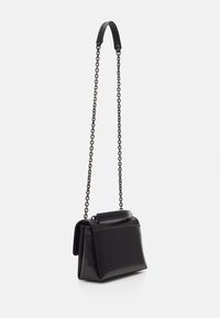 Borsa nera con forma strutturata, dotata di una finitura liscia e di una tracolla a catena, esposta su uno sfondo bianco.