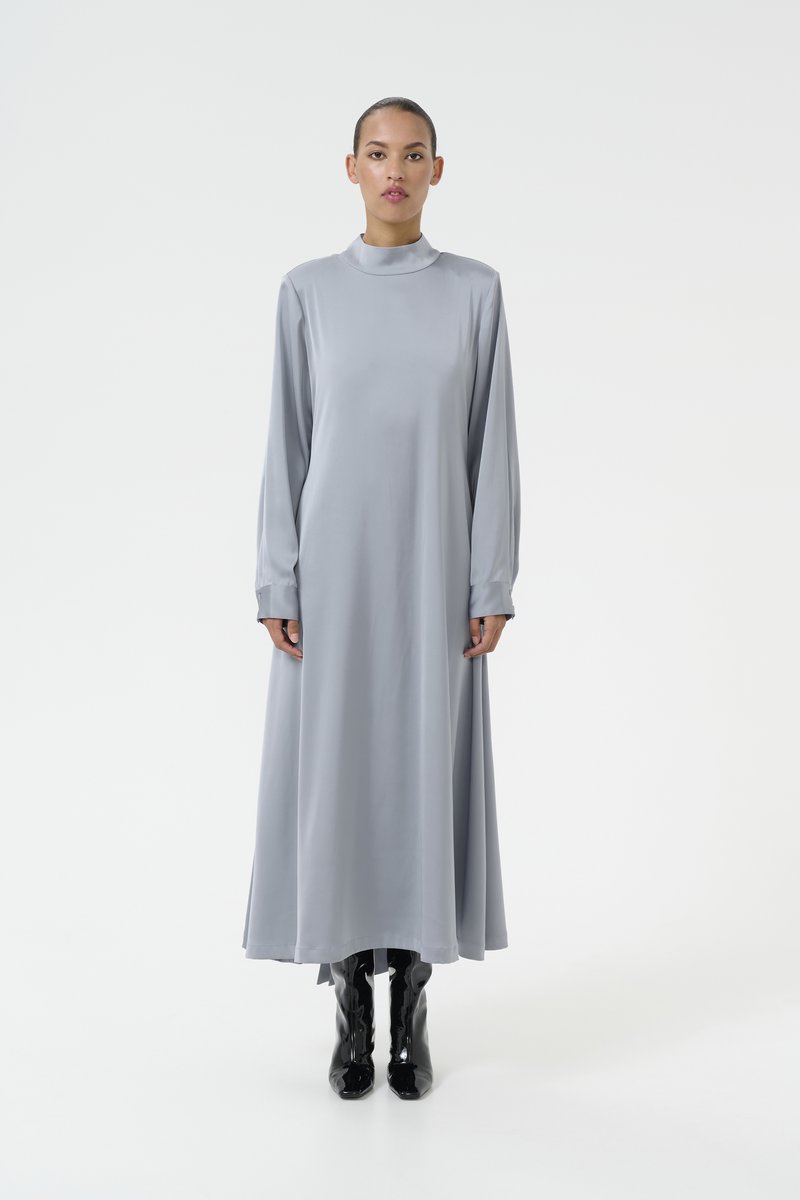 Robe longue grise en tissu lisse et léger, avec un col haut, des manches longues et un design fluide, arrivant jusqu'aux chevilles.