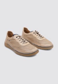 Zapatos de piel perforada beige claro con cordones grises, punta redondeada y suela de goma flexible que presenta un patrón texturizado en los laterales.