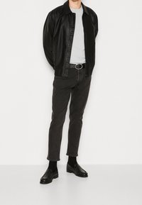 Musta nahkatakki, vaaleanharmaa t-paita, tummat farkut, musta vyö metallisoljella, mustat loafersit, sileät materiaalit, yksinkertainen muotoilu.