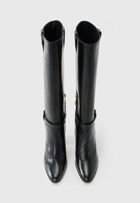 Pair of tall black leather boots with pointed toes and side zippers, shown upright on a light background.