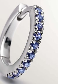 Aro de plata que presenta una fila de piedras redondas, de azul claro a oscuro, dispuestas en un diseño de garras, con un acabado pulido y una textura suave.