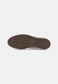 Hnědá gumová podrážka boty s diamantovým a lineárním vzorem podešve, bílými bočními stěnami a značkovými detaily. Celkově hladká textura.
