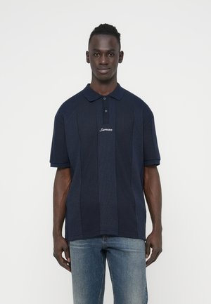 Marineblå kortærmet polo med en tekstureret strikket design, der har en placket med tre knapper og et broderet logo på brystet.