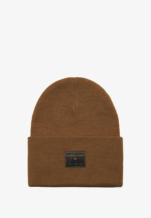 Brun strikket hue med ombuk, prydet med et sort rektangulært mærke med hvid tekst. Blød tekstur og tætsiddende form for varme.
