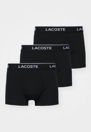 Schwarze Boxershorts im Dreierpack. Hergestellt aus einem glatten, dehnbaren Stoff mit einem weißen Bund, der "Lacoste" in fetter Schrift zeigt.