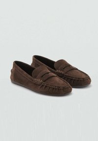 Mocassins en daim marron avec une semelle plate, un bout arrondi et une couture décorative. Présente un design élégant avec un détail de frange discret.