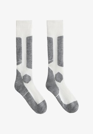 Kniehoge sokken met een witte basis en grijze geometrische patronen, voorzien van een hexagonaal accent en contrasterende grijze ribbelgebieden voor textuur.