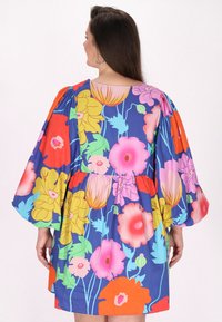 Abito a maniche corte con sfondo blu e vivaci motivi floreali in rosa, giallo e arancione; vestibilità rilassata con vita arricciata.