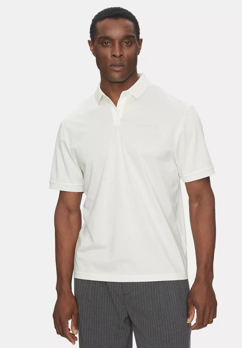 Polo shirt bianca a maniche corte e colletto, con un branding discreto. Realizzata in materiale liscio, offre un design classico.