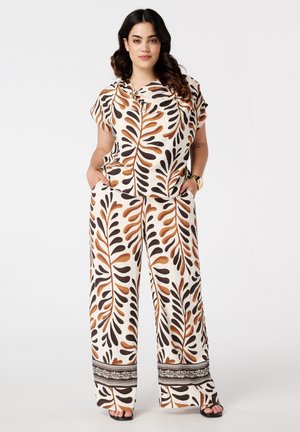 Twee-delige outfit met een kortarmige top en wijde broek in een crèmekleurige stof met bruine en zwarte bladerenpatronen en decoratieve afwerking.