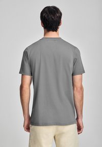 Camiseta gris de manga corta, material de algodón, diseño de cuello redondo, textura lisa sin patrones, vista trasera, dobladillo a la altura de la cintura.