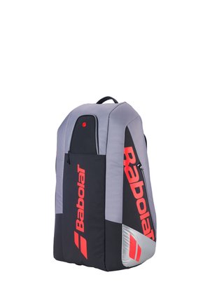 Høj sort og grå Babolat sportrygsæk med stort rødt logo og lynlåslommer, stående oprejst på hvid baggrund.