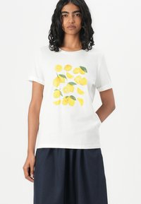 Weißes Baumwoll-T-Shirt mit einem gelben Zitronenmotiv und grünen Blättern. Kurze Ärmel, runder Ausschnitt, gerade Passform und weiche Textur.