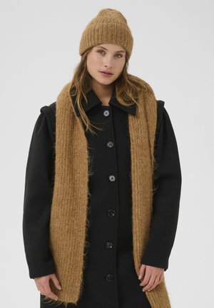 Schwarzer Wollmantel mit sechs Knöpfen, kragenförmiges Design, kombiniert mit einem strukturierten, gerippten Kamel-Schal und passender Mütze aus Strickmaterial.