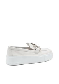 Witte leren instapschoenen met een solide witte plateauzool, voorzien van een decoratieve metalen ketting over de middenvoet voor extra detail.