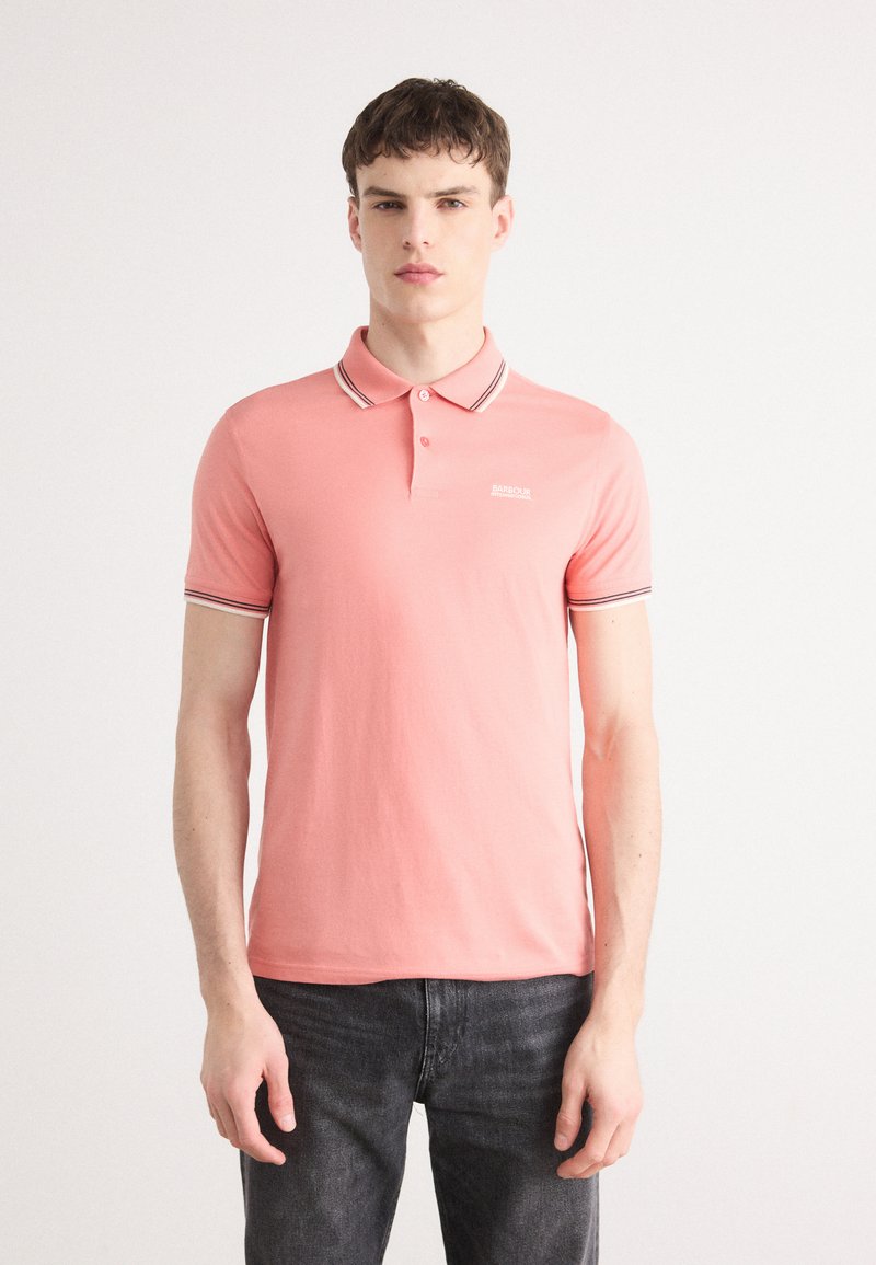 Polo en coton rose avec une coupe ajustée, dotée d'un col et d'accents rayés sur le col et les manches. Logo minimaliste sur la poitrine.
