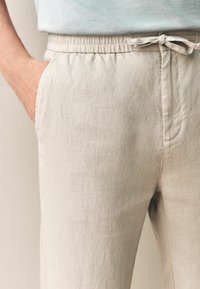 Lys beige linned bukser med elastisk talje og justerbar snor, med sidelommer og en glat, struktureret overflade.