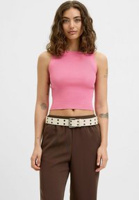 Rožinė raštuota trumpa palaidinė su aukštu kaklu, derinama su rudos spalvos kelnėmis ir baltu diržu, papuoštu metaliniais blizgučiais. Sklandi audinio tekstūra.