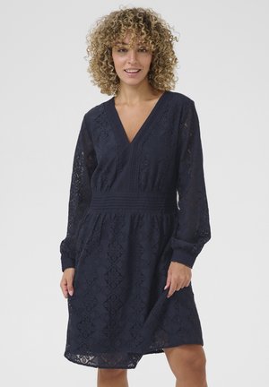Navy blue lace dress with long sheer sleeves, V-neckline, and a textured waistband. Floral and diamond patterns throughout the fabric.