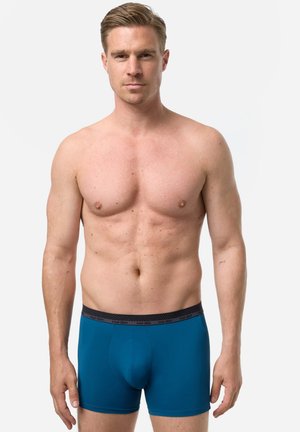 Herre boxershorts i livlig teal med en sort linning. Stoffet virker blødt og glat med en tætsiddende pasform og en funktionel lomme.