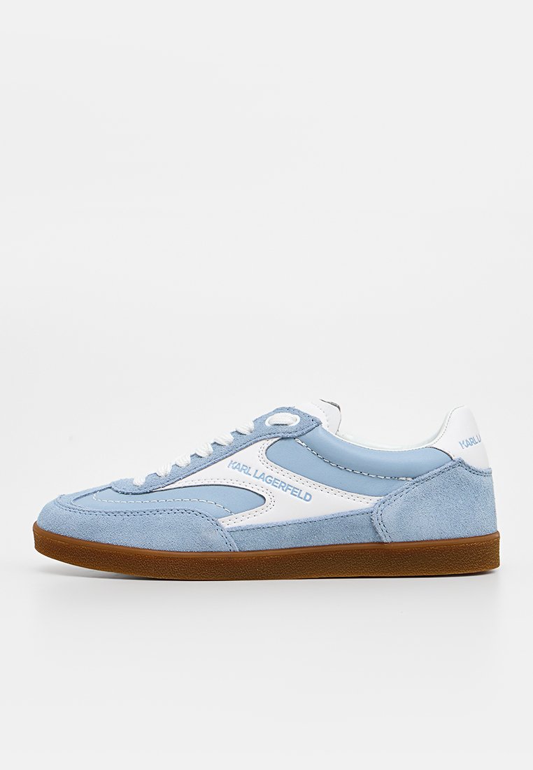 Zapatilla azul claro y blanca con paneles de ante y cuero, suela de goma marrón, cordones blancos y logotipo "KARL LAGERFELD" en el lateral y el talón.
