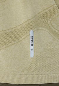 Hellbeiger Activewear-Stoff mit strukturierten Mustern, Mesh-Akzenten und einem silbernen Etikett mit der Aufschrift "ACTIBREEZE". Glattes, atmungsaktives Material.