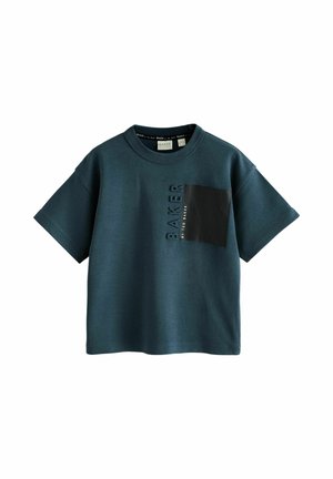 Mørk teal kortærmet skjorte med rund hals, sort firkantet brystlomme og lodret "BAKER BY TED BAKER" tekst ved siden af lommen.