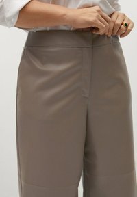 Pantaloni grigi su misura con una texture liscia, dal design a gamba larga e una cintura a vita media, caratterizzati da un sottile dettaglio di cucitura frontale.