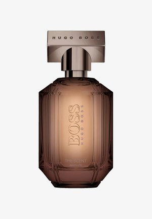 Brun glasparfymflaska med en texturerad design, försedd med en metallisk, rektangulär kork. Etiketten lyder "BOSS THE SCENT ABSOLUTE."