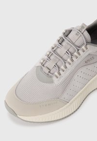 Hellgraue Sneaker mit einem Obermaterial aus Mesh, gepolstertem Kragen und tonal abgestimmten Akzenten. Mit Perforationen an den Seiten und einer strukturierten Sohle mit Branding.