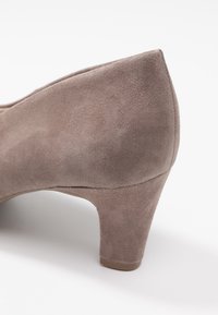 Chaussure à talon haut en daim gris avec un bout arrondi et un talon étroit. Texture lisse avec un léger éclat. Vue de profil montrant une forme profilée.