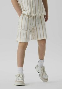 Vita randiga shorts med beiga linjer, tillverkade i texturerad tyg. Har sidofickor och en avslappnad passform, matchat med vita sneakers och strumpor.