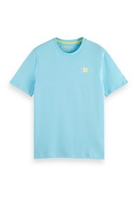 Camiseta de algodón azul claro con mangas cortas y cuello redondo. Un pequeño logo cuadrado amarillo está situado en el pecho izquierdo. Textura suave.