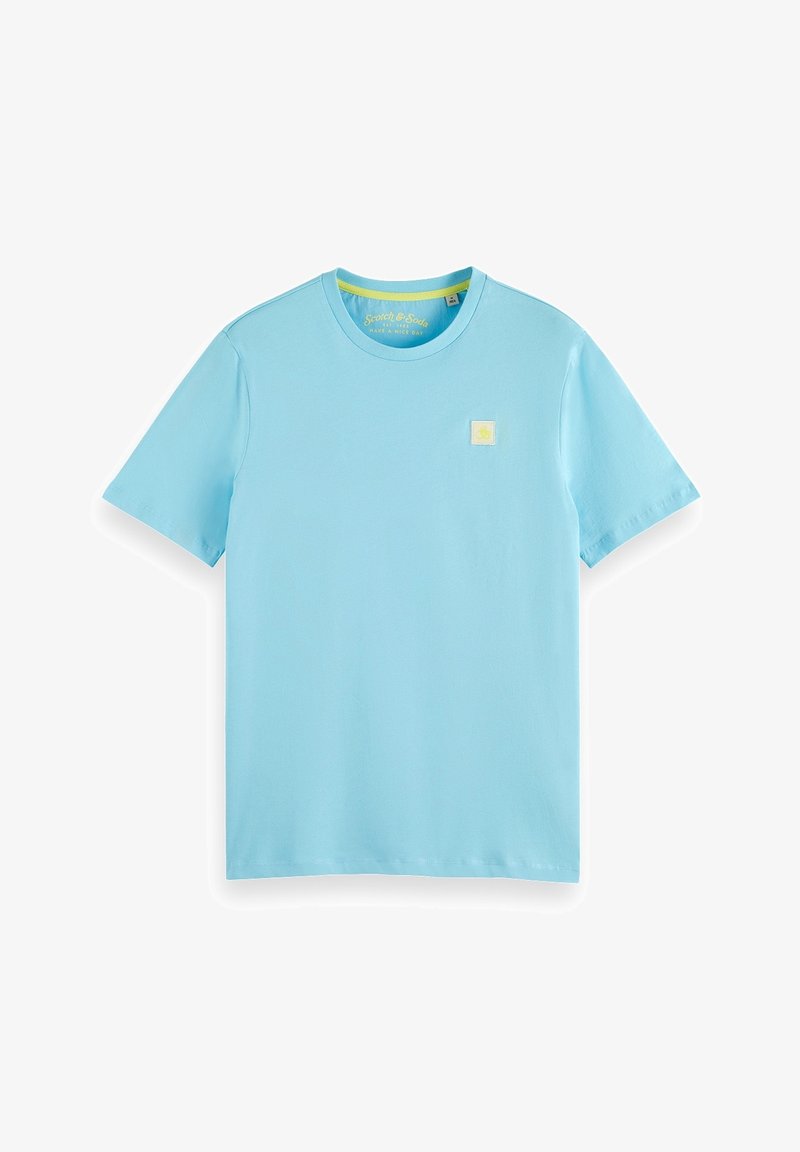 Světle modré tričko z bavlny s krátkými rukávy a kulatým výstřihem. Malé žluté čtvercové logo je umístěno na levé straně hrudi. Hladká textura.