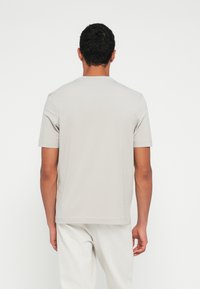 Jasnoszary bawełniany t-shirt z krótkimi rękawami i okrągłym dekoltem. Zaprojektowany z myślą o luźnym kroju, ukazujący gładką teksturę i minimalne szwy.