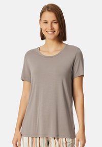 T-shirt grigio chiaro a maniche corte con scollatura tonda, texture liscia e vestibilità rilassata, abbinato a pantaloni a righe con tonalità terrose.