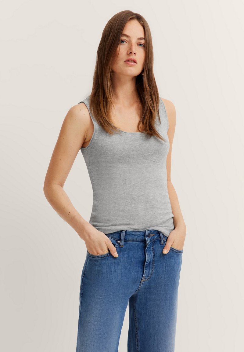 Gray sleeveless top made of soft fabric, paired with blue denim jeans. The top has a square neckline and a fitted silhouette.