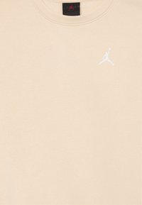 Sudadera beige, mezcla de algodón, cuello redondo, logo de Jordan bordado en blanco en el pecho, textura suave, sin patrones ni herrajes visibles.