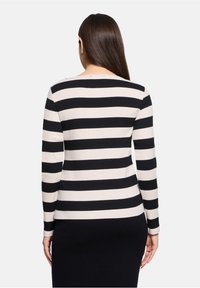 Lange mouwen top in crème en zwarte horizontale strepen, gemaakt van zachte stof met een ronde halslijn en een getailleerd ontwerp.