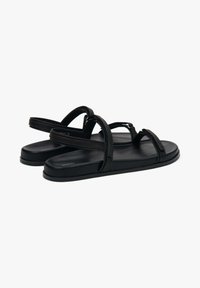 Zwarte platte sandalen van soepel synthetisch materiaal; beschikken over meerdere slanke banden en een gevormde zool voor comfort.