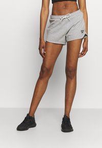 Harmaat puuvillahousut, joissa on joustava vyötärö ja narusolmuke. Vasemmassa reidessä Reebok-logo. Yhdistetty mustien urheilukenkiä kanssa.