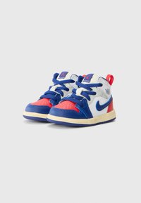 Zapatillas azul y roja con acentos blancos, con parte superior de cuero suave, puntera redonda, lengüeta acolchada y suela de goma texturizada.