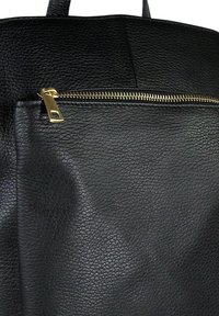 Zwarte leren rugzak met een opvallende ritszak en gouden hardware-accenten, voorzien van een gestructureerde silhouet en stevige banden.