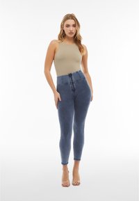 Jeans de denim de cintura alta en azul oscuro con un acabado suave, que cuentan con un cierre de cremallera y botón, y un ligero estiramiento para mayor comodidad.