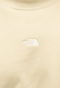 Μπεζ φούτερ με ριμπ γιακά, με λευκό κεντημένο λογότυπο της The North Face. Μαλακή υφή υφάσματος με εφαρμοστή σιλουέτα.