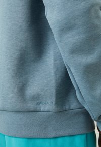 Svetlomodrý sveter vyrobený z textúrovanej tkaniny, s rebrovaným lemom a manžetami. Vyšívané logo "DRI-FIT" na spodnej časti prednej strany.